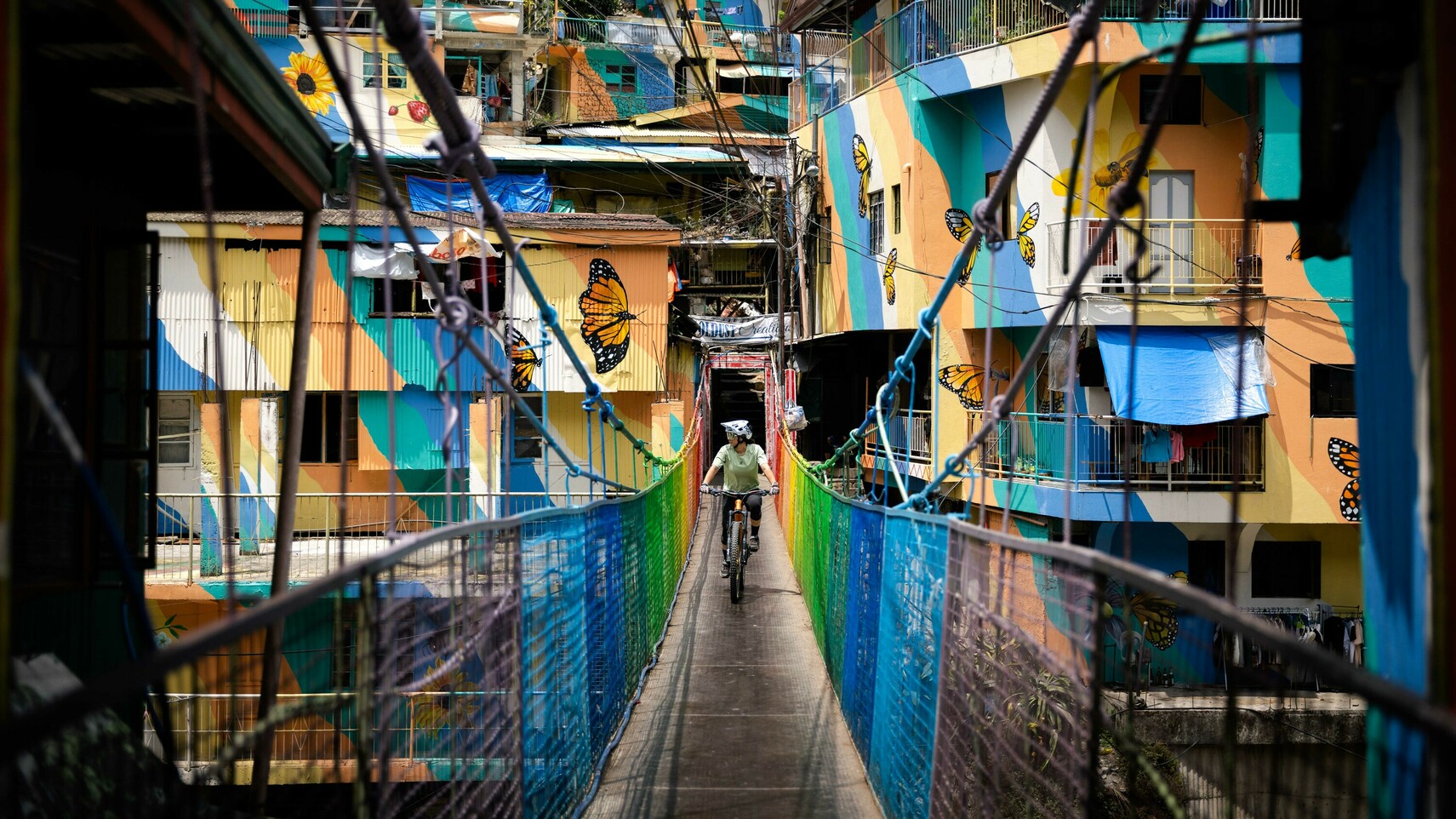 Samantha bikes on a bridge in a colorful village