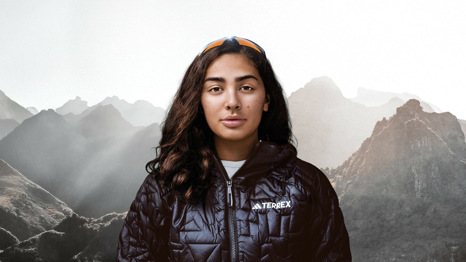 A person wearing a black jacket with "TERREX" on it stands in front of a mountainous landscape, embodying the adventurous spirit of the EOFT program 2024.